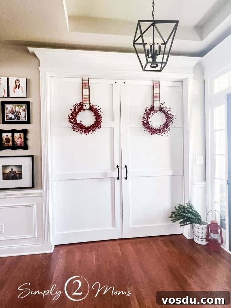 Country Chic Christmas Home Tour That Inspires Holiday Decorating 7 Large white classic double barn doors in a foyer decorated for Christmas with red berry wreaths hung with Christmas plaid ribbon