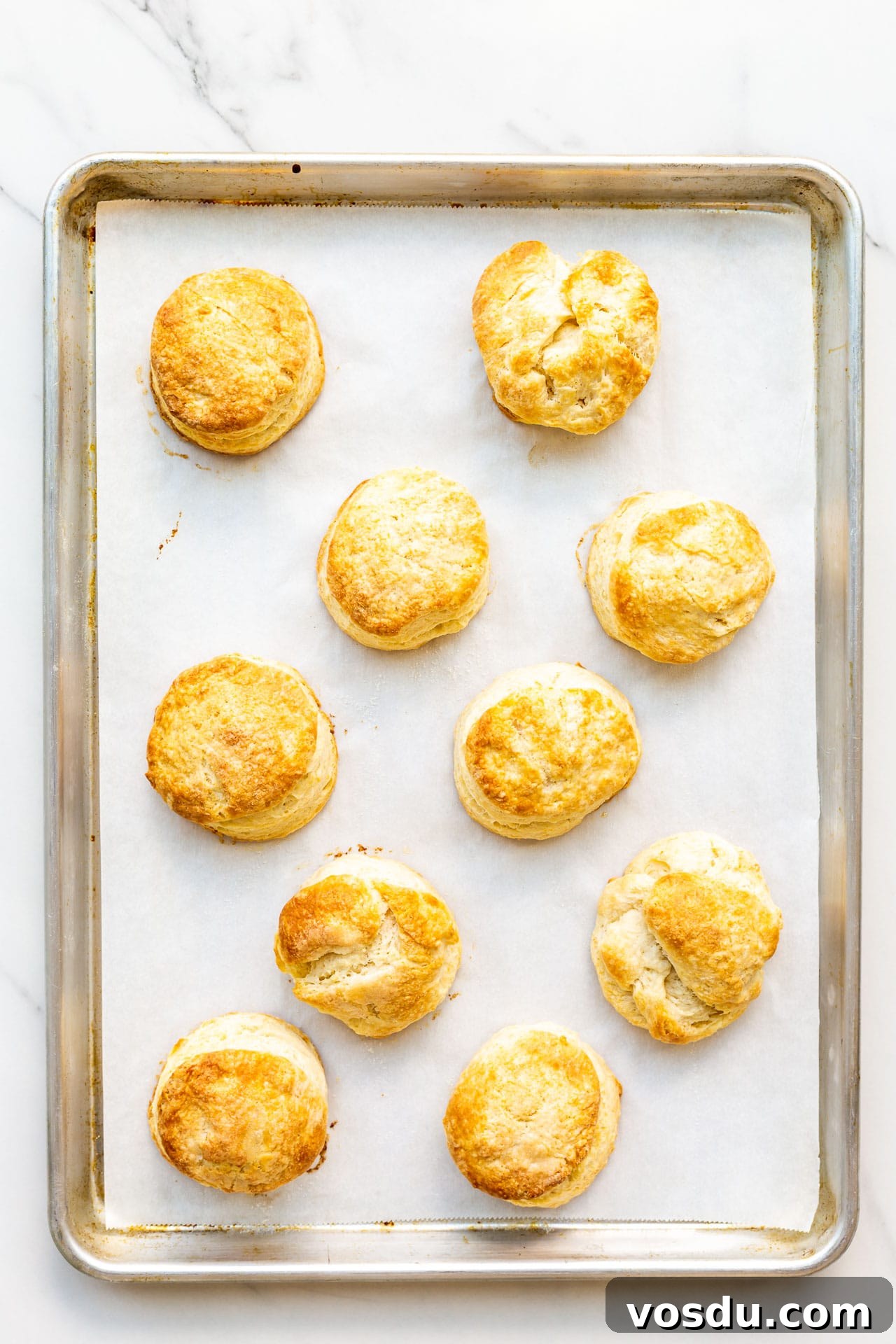 A parchment-lined sheet pan with golden brown homemade biscuits