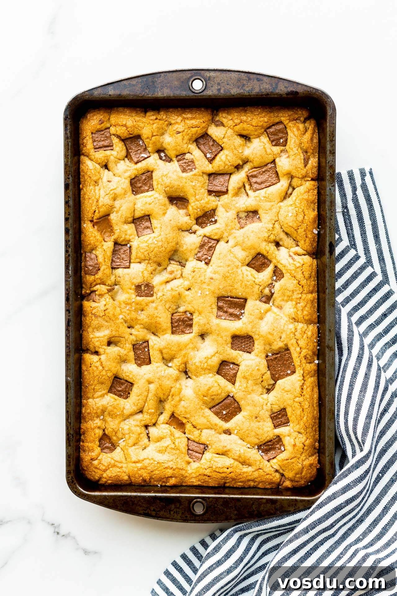 A rectangular pan of Skor blondie bars freshly baked with a striped towel