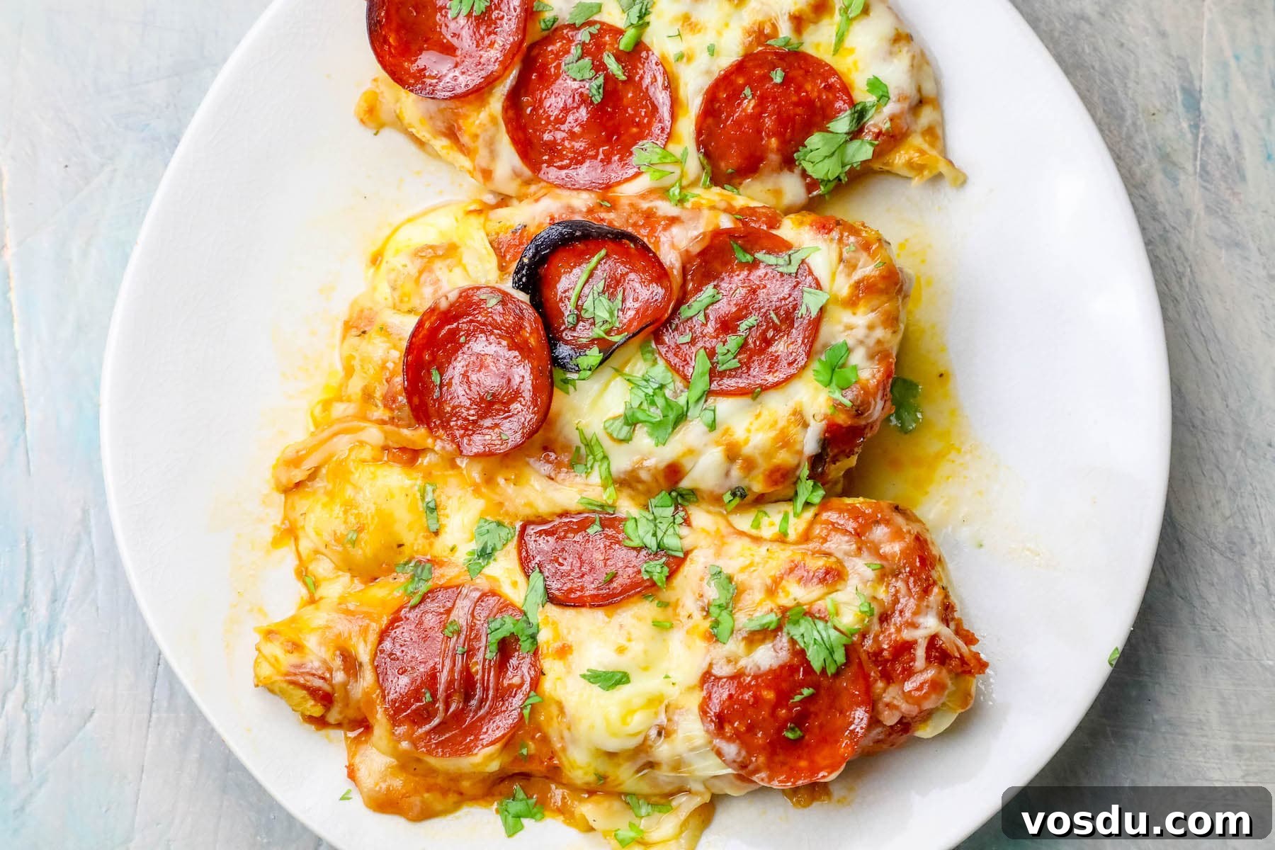Keto Low-Carb Cheesy Pizza Chicken Recipe 3 chicken smothered in cheese and pepperonis on a plate