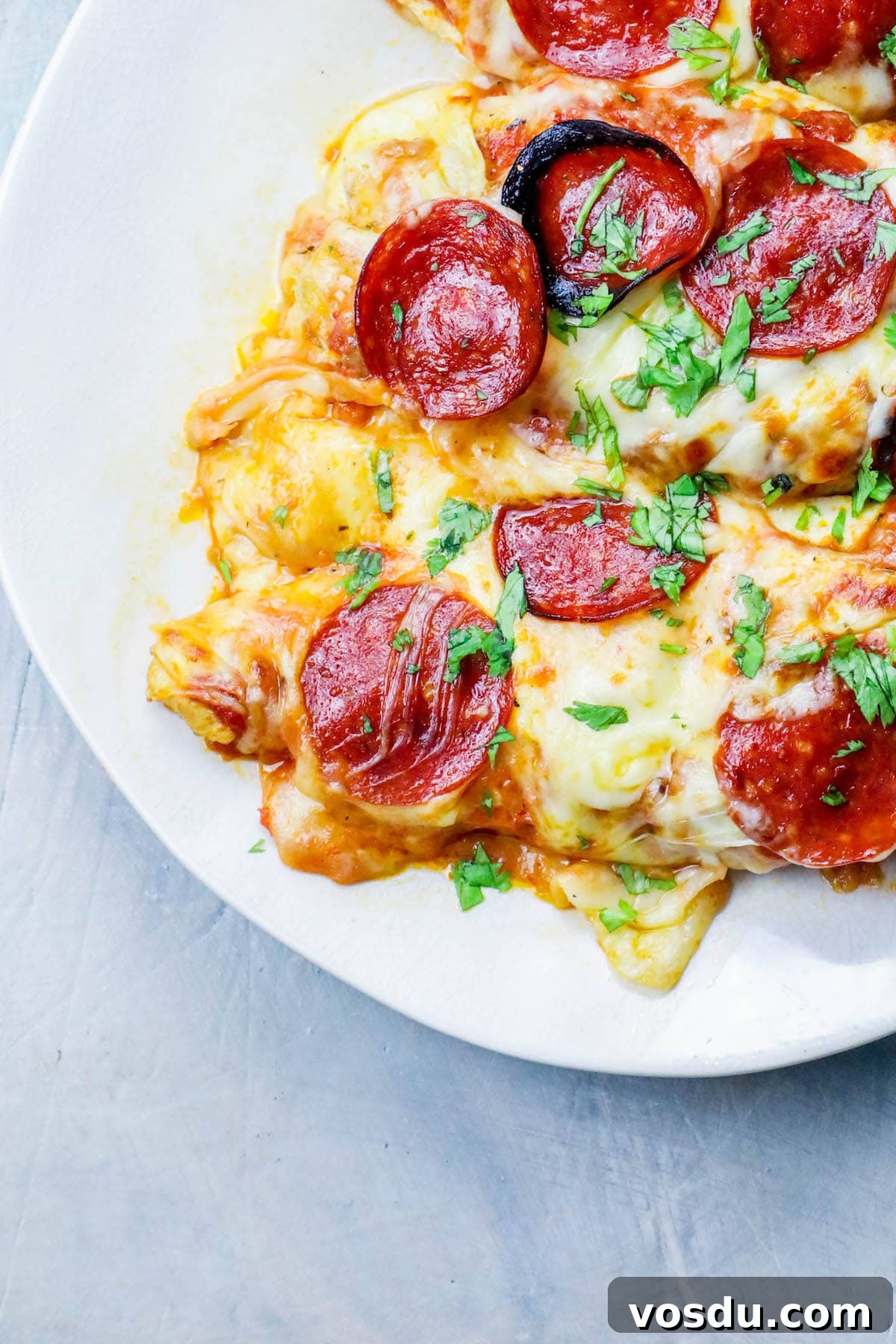 Keto Low-Carb Cheesy Pizza Chicken Recipe 4 chicken smothered in cheese and pepperonis on a plate