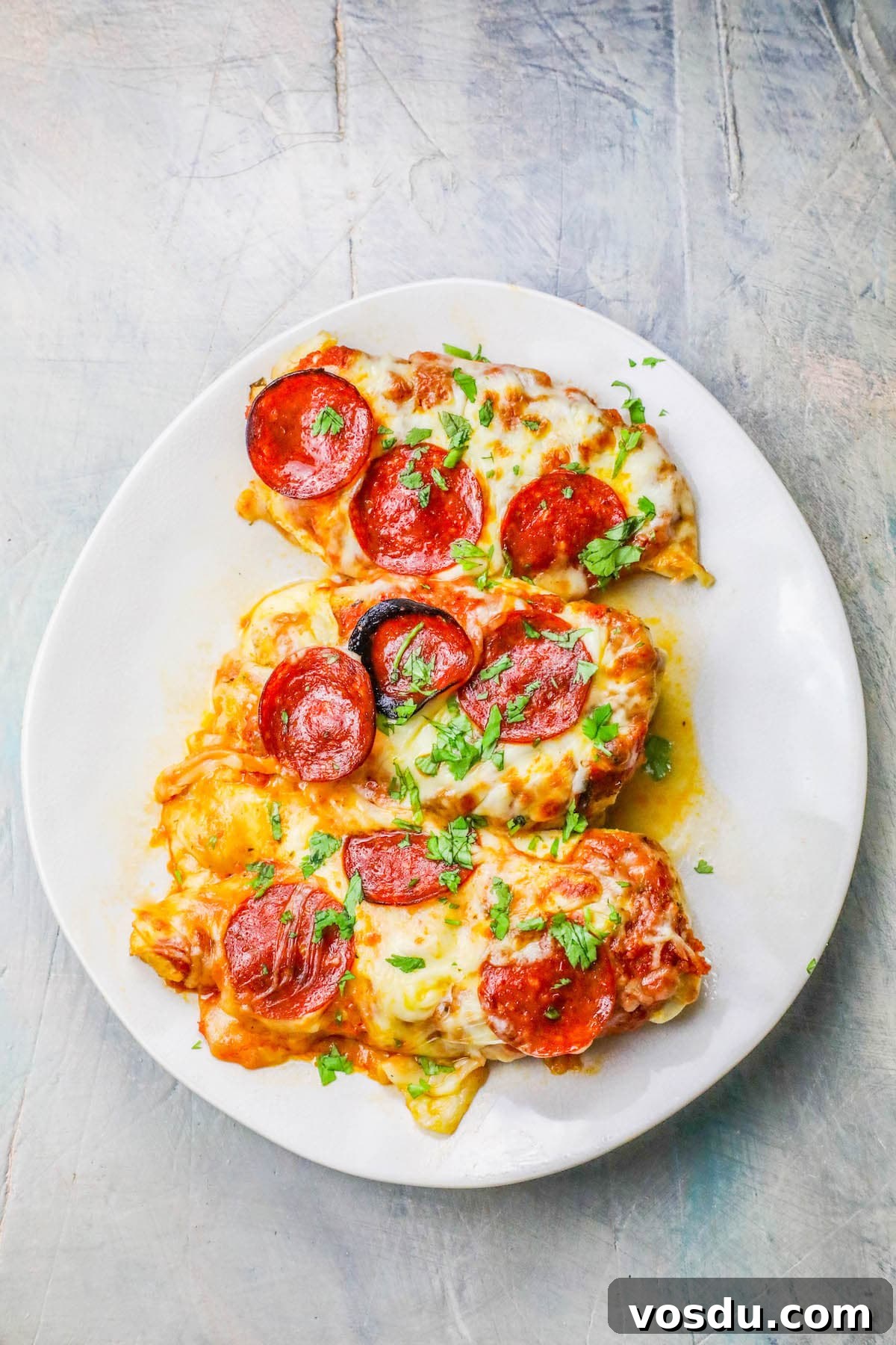 Keto Low-Carb Cheesy Pizza Chicken Recipe 5 chicken smothered in cheese and pepperonis on a plate