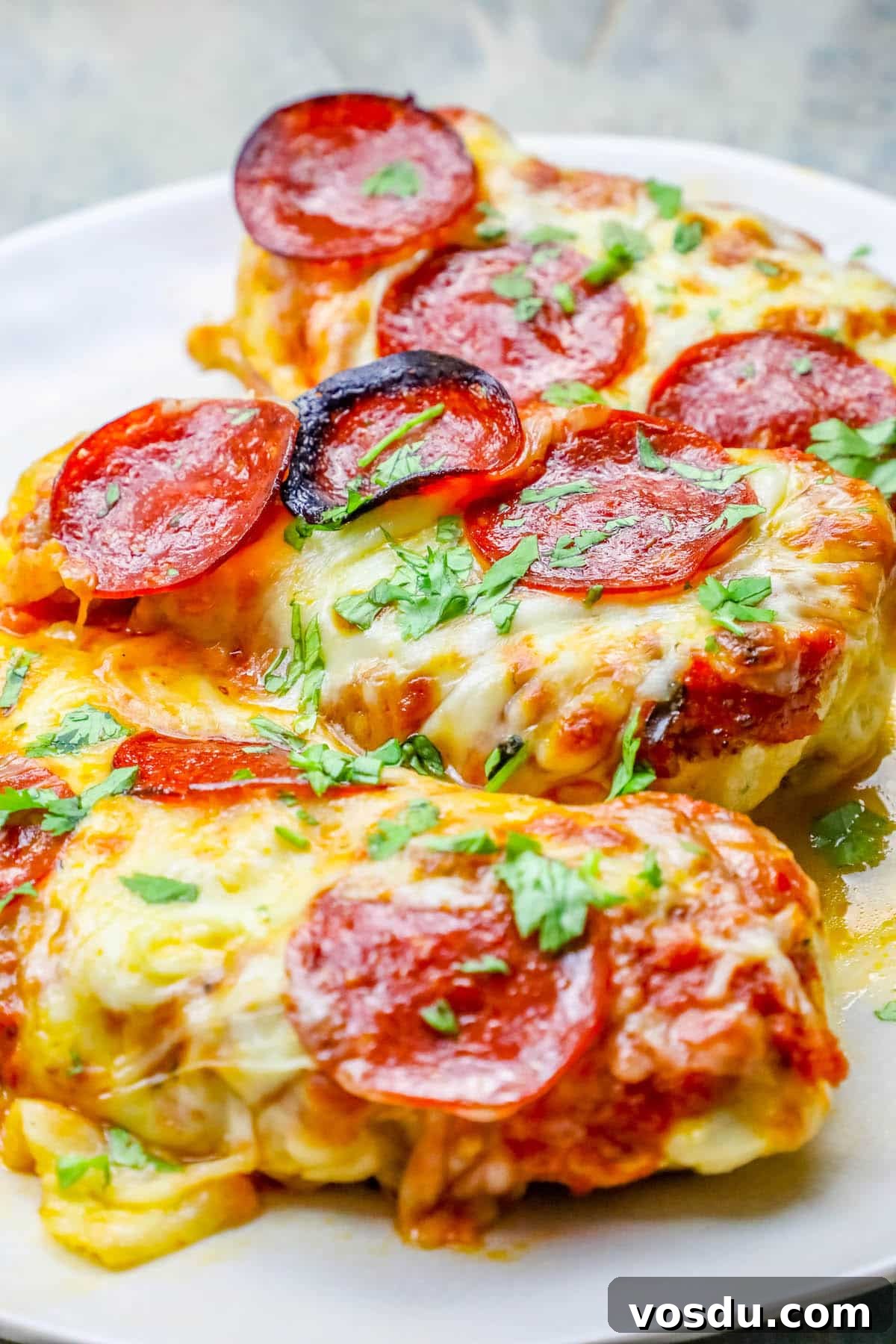Keto Low-Carb Cheesy Pizza Chicken Recipe 6 chicken smothered in cheese and pepperonis on a plate