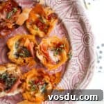 Baked blue cheese, prosciutto, sweet chilli bites on a small pink plate.