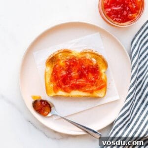 Pink grapefruit marmalade on toast on a plate with a striped linen.