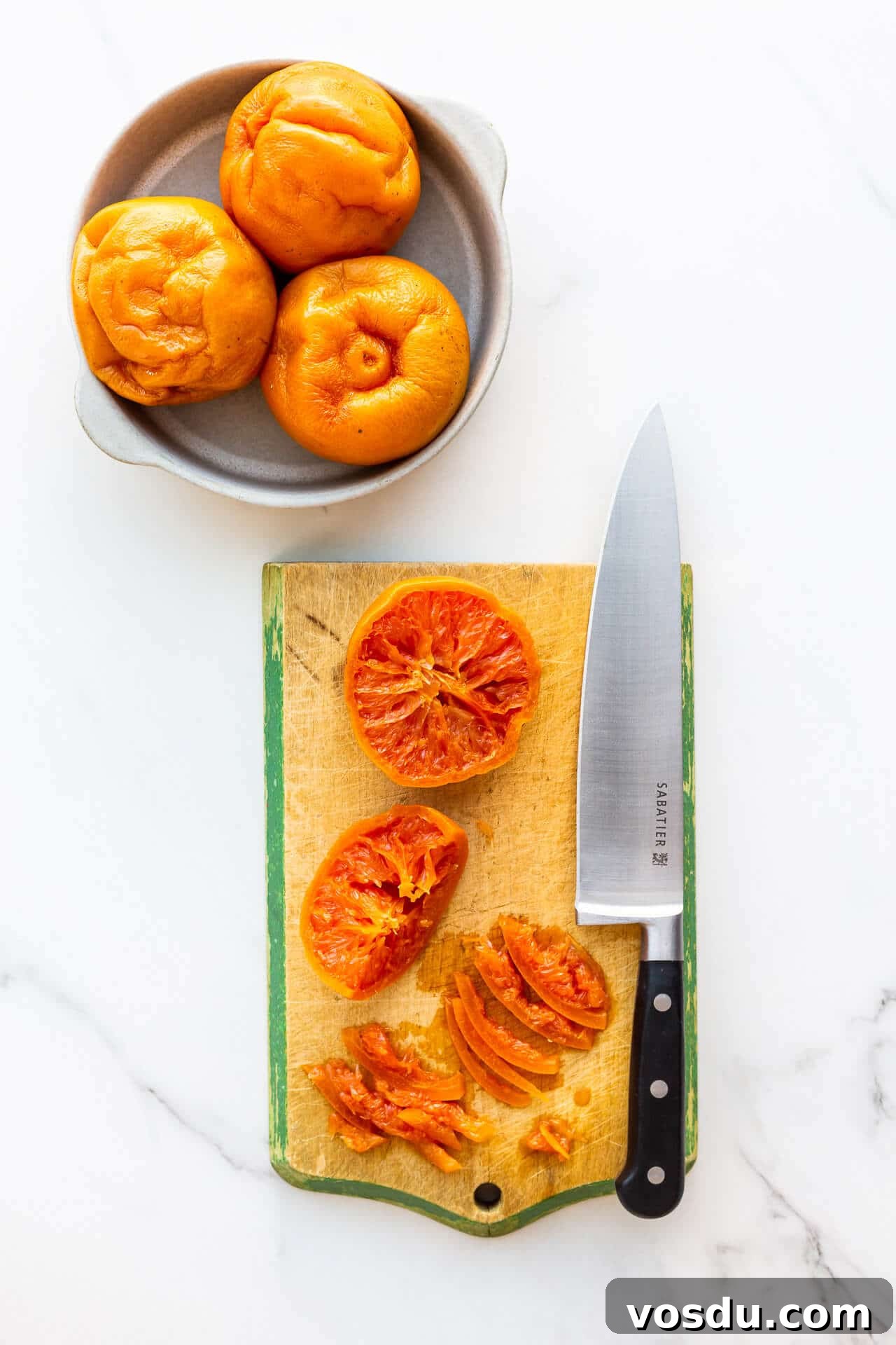 Slicing boiled grapefruit on a cutting board with a chef's knife to make marmalade.