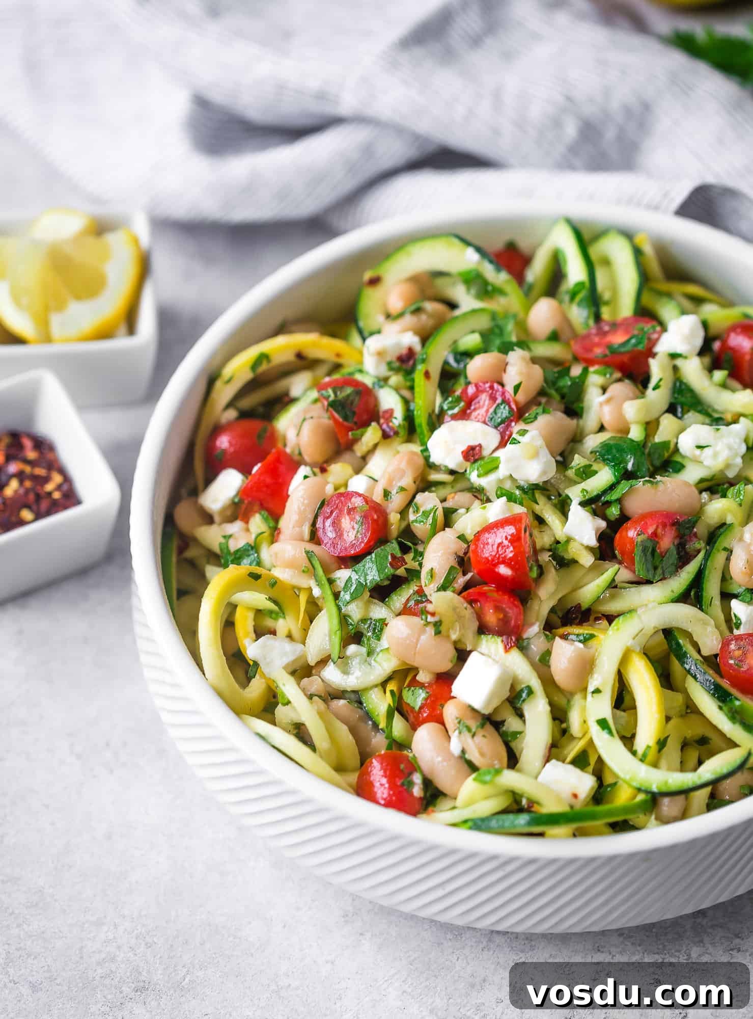 This healthy and easy to make zucchini noodle salad is hearty enough to serve as a vegetarian meal, but it can also serve as a flavorful side salad that everyone will love. Get the recipe on RachelCooks.com! Zucchini noodle salad with fresh herbs, tomatoes, white beans.