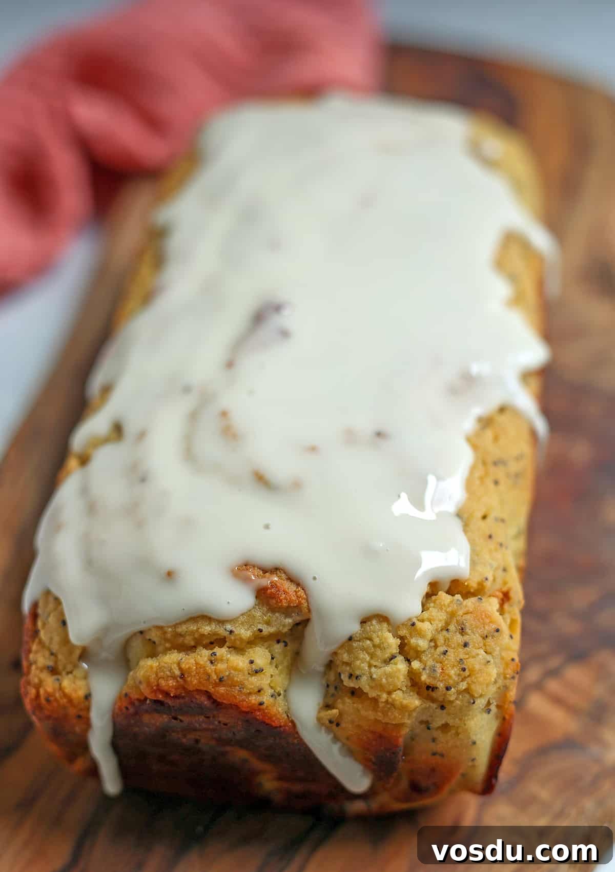 A loaf of lemon poppy seed bread on a cutting board, the top covered in a glaze.