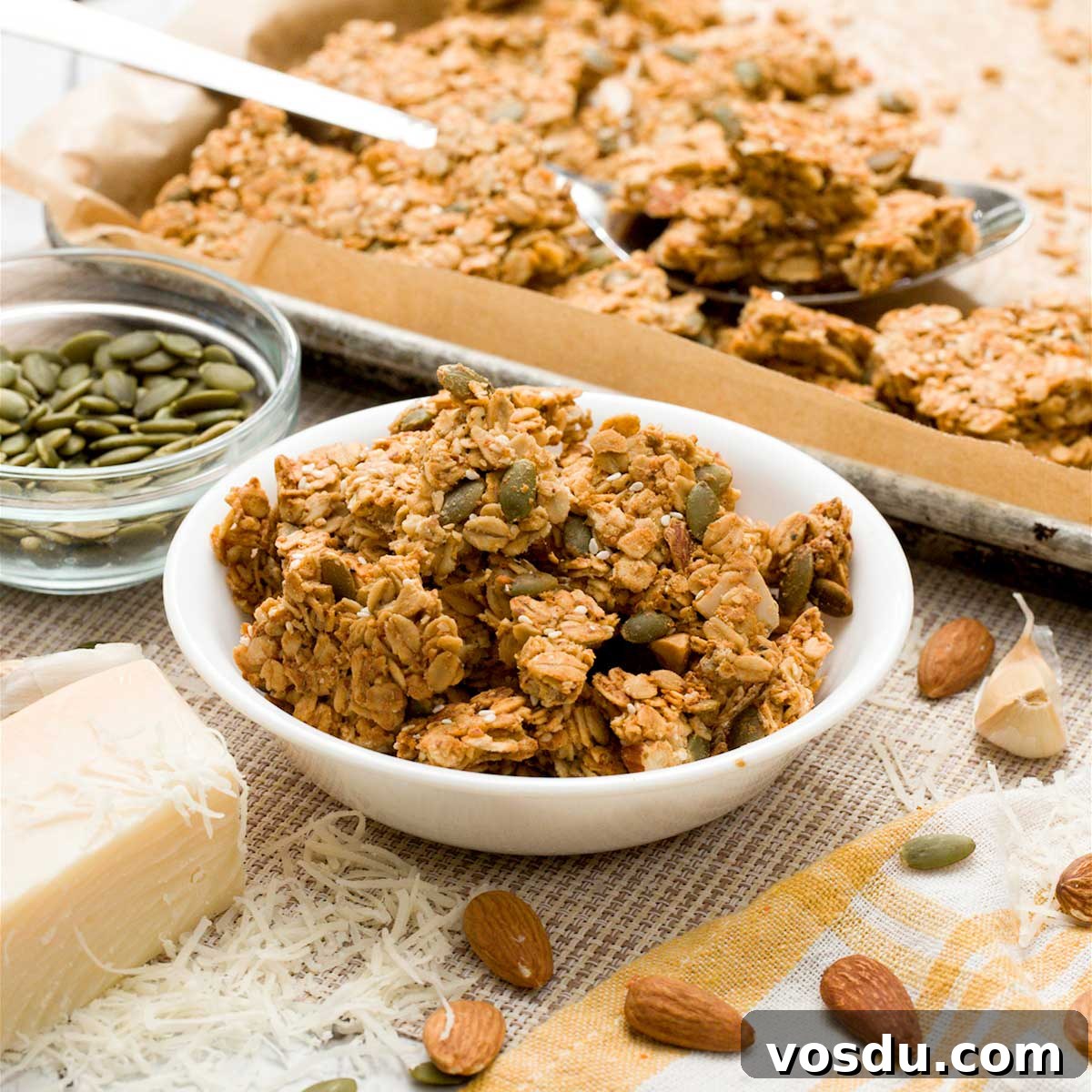A bowl of gluten-free savory granola with almonds, Parmesan cheese, pumpkin seeds, in a white bowl.