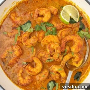 Thai Coconut Shrimp Curry Recipe — Creamy Coconut Prawn Curry 10 A pot of red curry shrimp with a spoon.