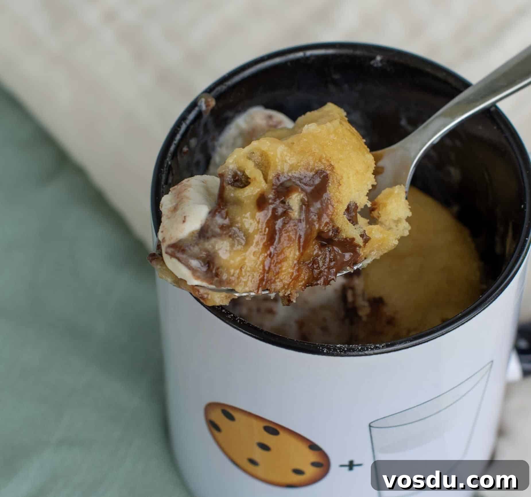 Sourdough Mug Cookie Recipe: Quick Single-Serve Treat 2 Close-up of a spoon lifting a soft, gooey bite of sourdough cookie from a mug, with melted chocolate and a bit of ice cream visible.