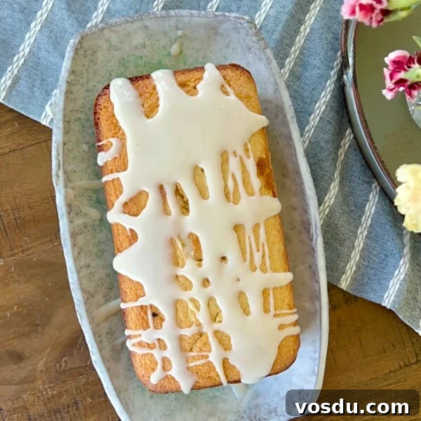 Sourdough discard loaf cake topped with a thick lemon glaze on a serving plate.