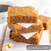 A stack of keto iced peanut butter bars with a cup of coffee in the background.