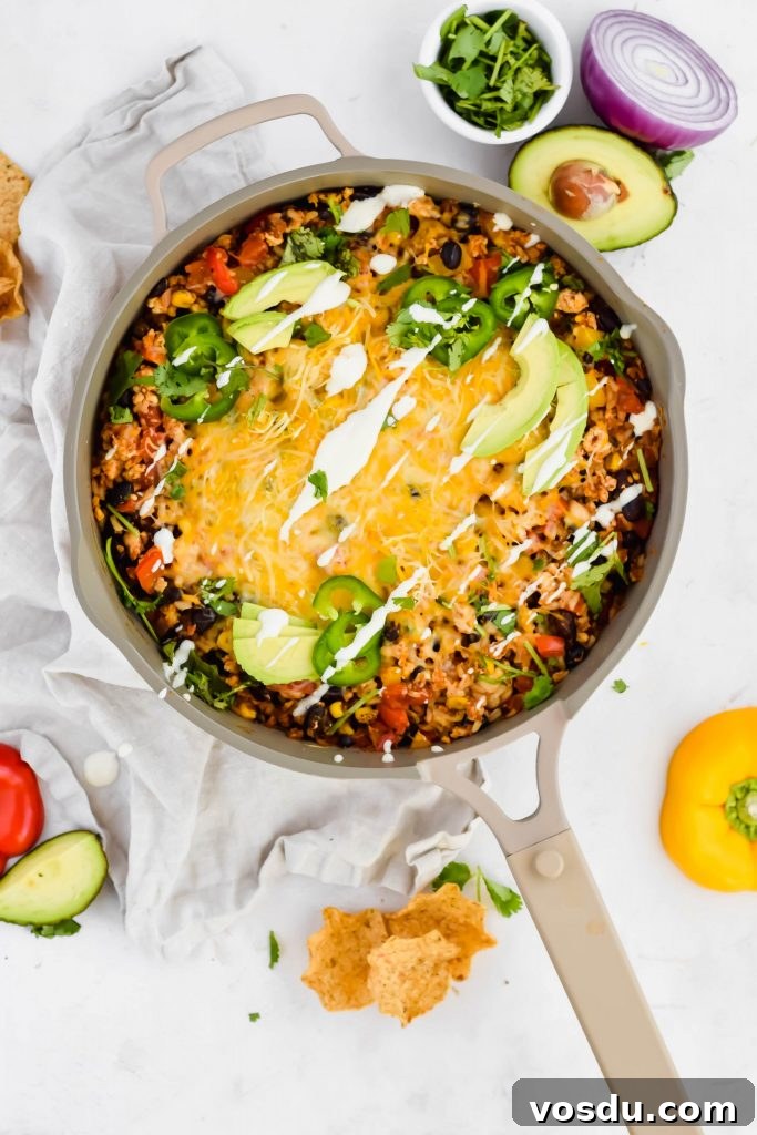 Readers' Top 10 Favorite Recipes of 2022 6 Overhead view of Cheesy Mexican Chicken Skillet in a tan pan surrounded by avocado, red onion, cilantro, chips, and bell pepper