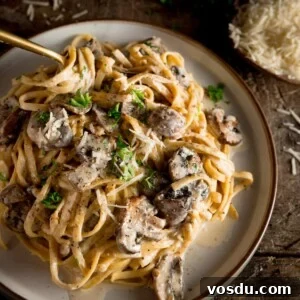 Creamy Mushroom Pasta Recipe with Garlic and Parmesan 12 a square shot of creamy mushroom pasta on a white plate with a spoon dug in