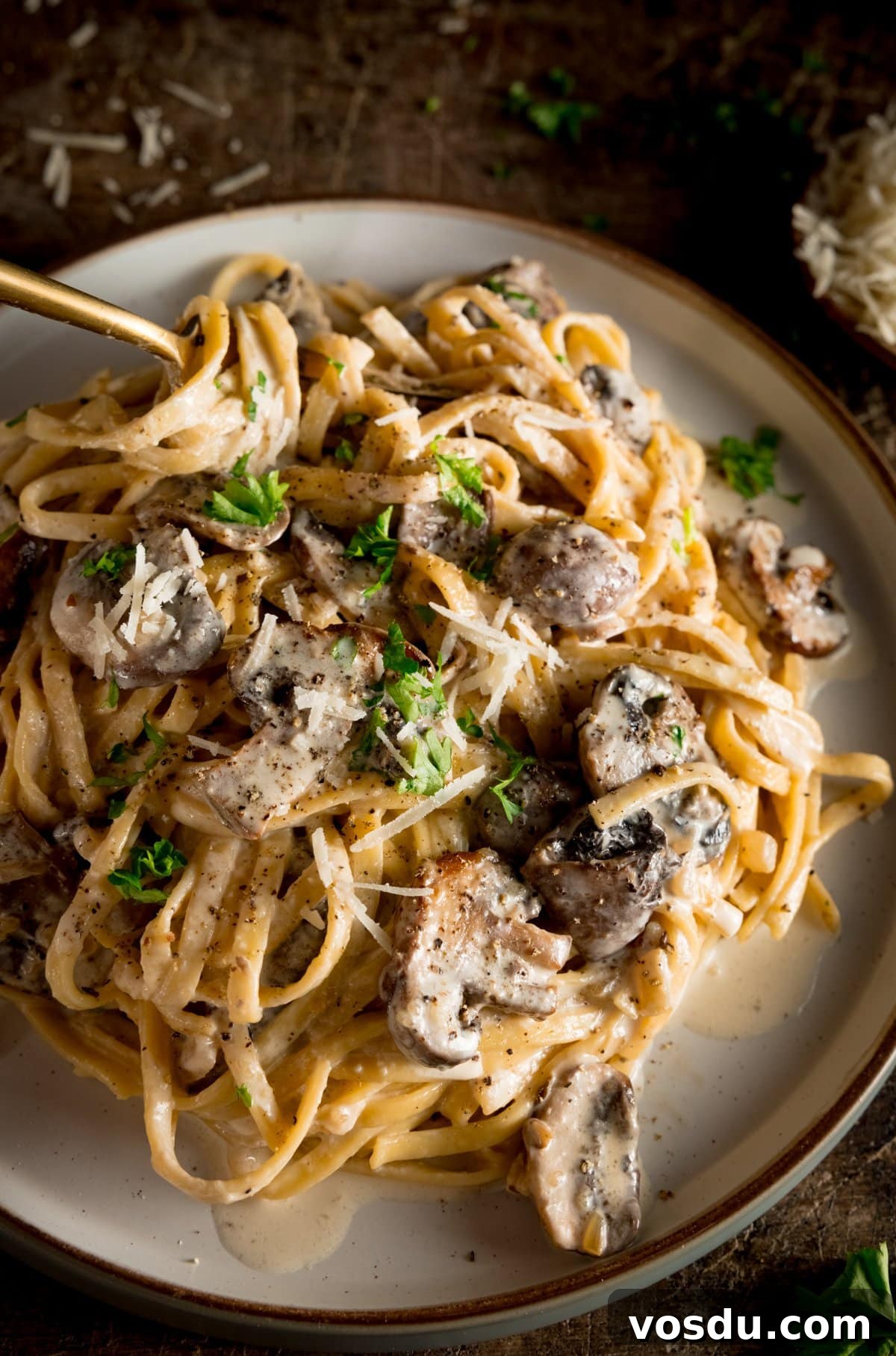 Creamy Mushroom Pasta Recipe with Garlic and Parmesan 5 A white plate piled high with creamy mushroom pasta with a spoon sticking out