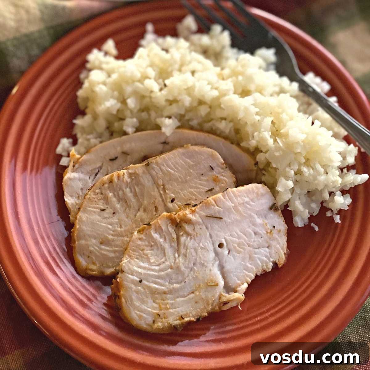 Juicy Oven-Baked Turkey Tenderloin with Herb Garlic Crust 2 Three slices of turkey tenderloin on a plate with cauliflower rice and a fork.