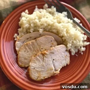 Juicy Oven-Baked Turkey Tenderloin with Herb Garlic Crust 6 Three slices of turkey tenderloin on a plate with cauliflower rice and a fork.
