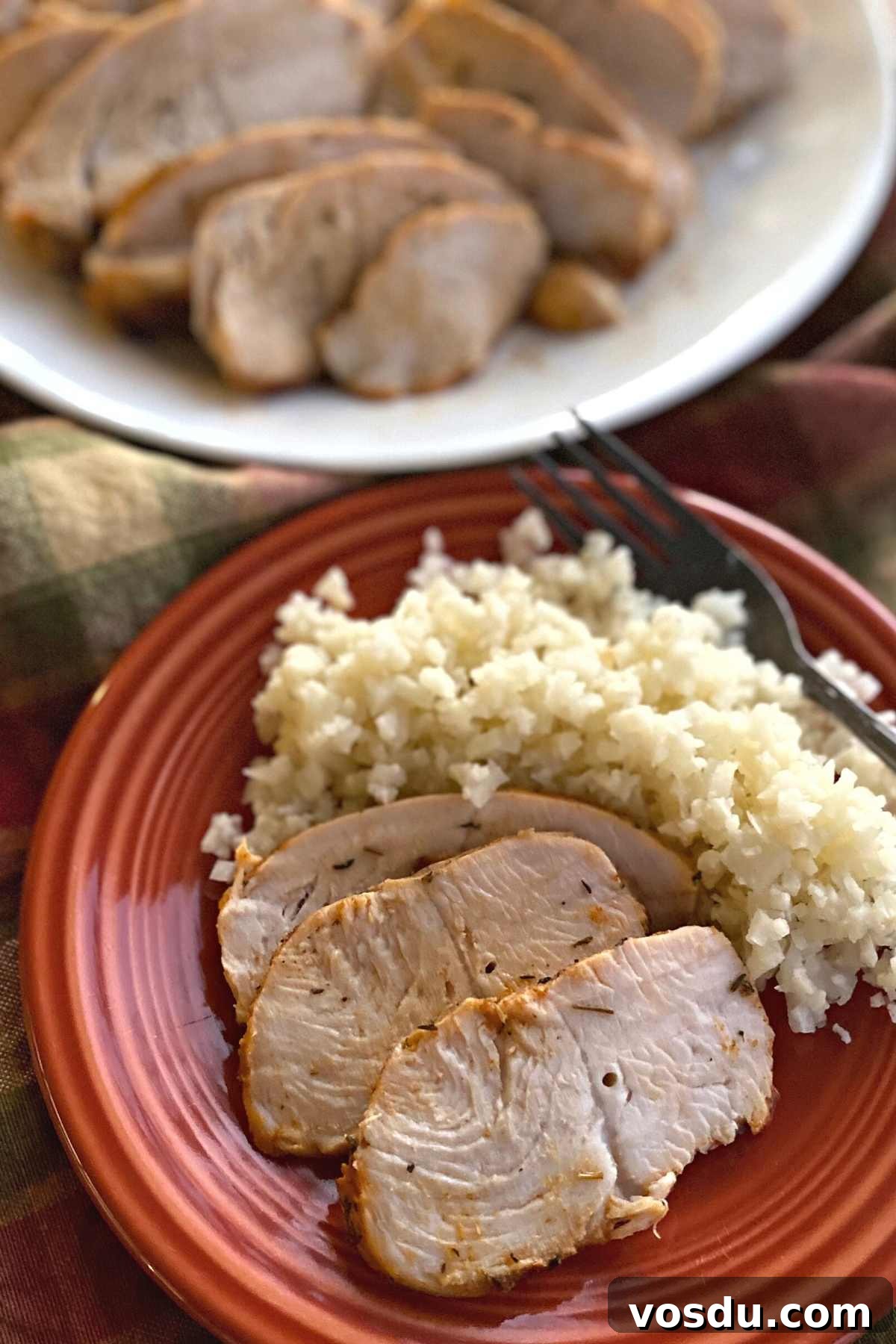 Juicy Oven-Baked Turkey Tenderloin with Herb Garlic Crust 5 Baked turkey tenderloin on plate with cauliflower rice with platter of sliced turkey behind it.