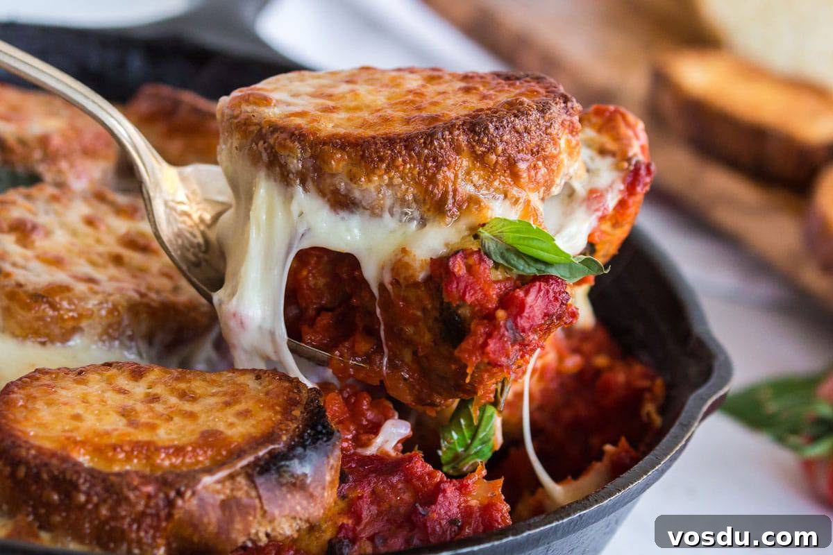 Cheesy Chicken Meatball Casserole with Tomato Basil Sauce 2 Scooping a portion of meatball sub casserole out of a skillet