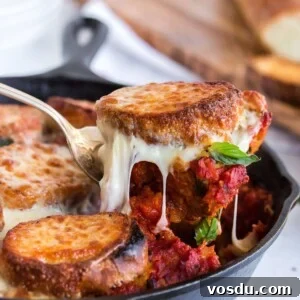 Cheesy Chicken Meatball Casserole with Tomato Basil Sauce 12 Scooping a portion of meatballs and bread out of skillet with melted cheese.