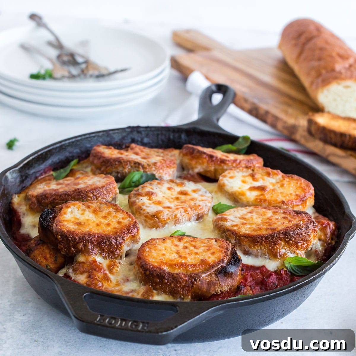 Cheesy Chicken Meatball Casserole with Tomato Basil Sauce 3 Skillet with sliced baguettes and melted cheese in red sauce.