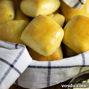 How to Make Texas Roadhouse-Style Rolls at Home 4 Texas Roadhouse rolls in a bowl with a striped linen