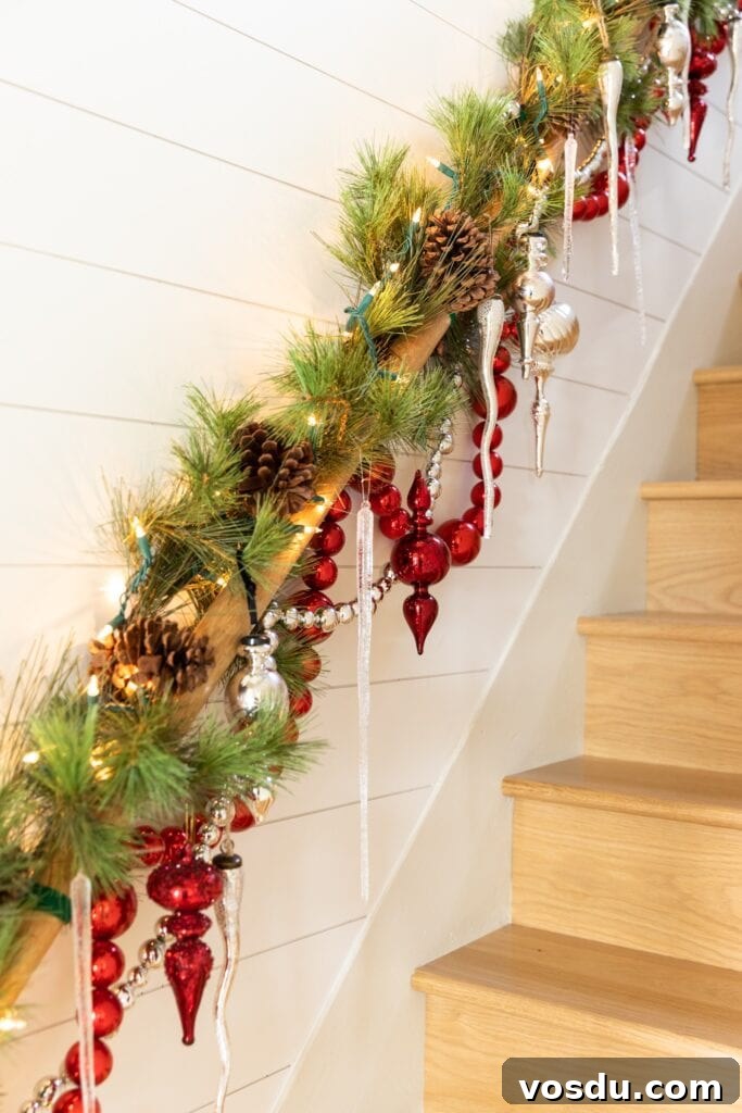 This Year’s Holiday Home Decor: Fresh Ideas to Transform Your Space 12 Red and silver ornaments and garland dangling from wood handrail in a stairwell topped with icicles