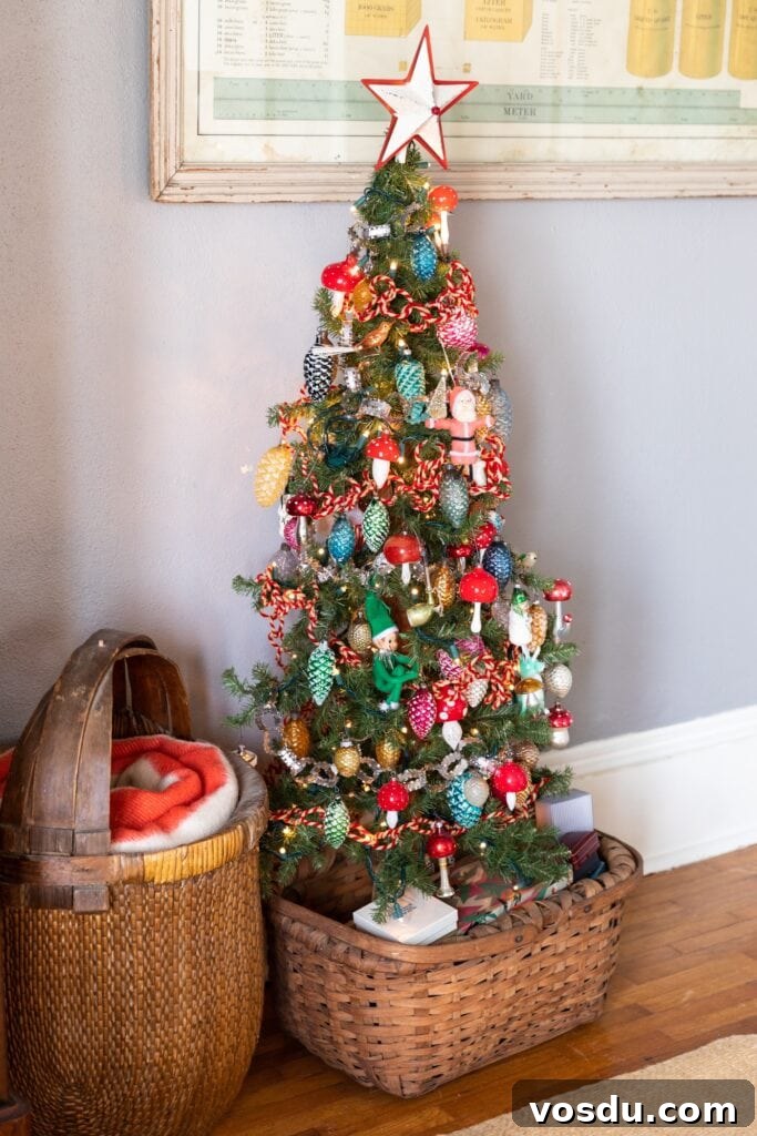 This Year’s Holiday Home Decor: Fresh Ideas to Transform Your Space 15 Half size Christmas tree covered with brightly colored vintage glass ornaments sitting in a basket with small vintage boxes piled all around the base