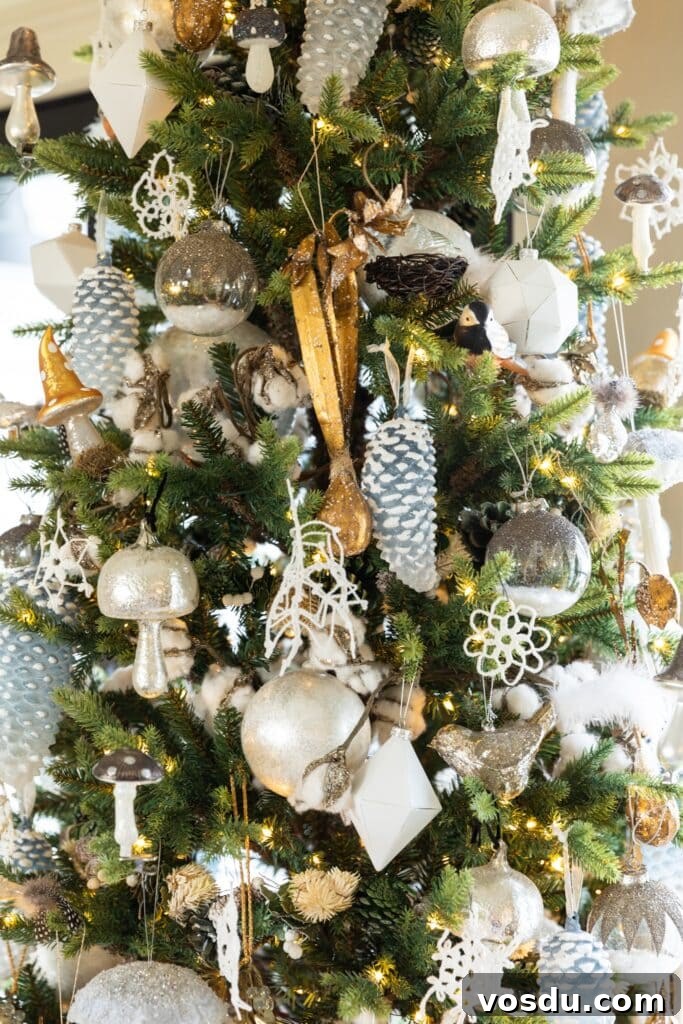This Year’s Holiday Home Decor: Fresh Ideas to Transform Your Space 17 Close up view of gold and silver and white ornaments hanging on tall skinny Christmas tree in front of French doors