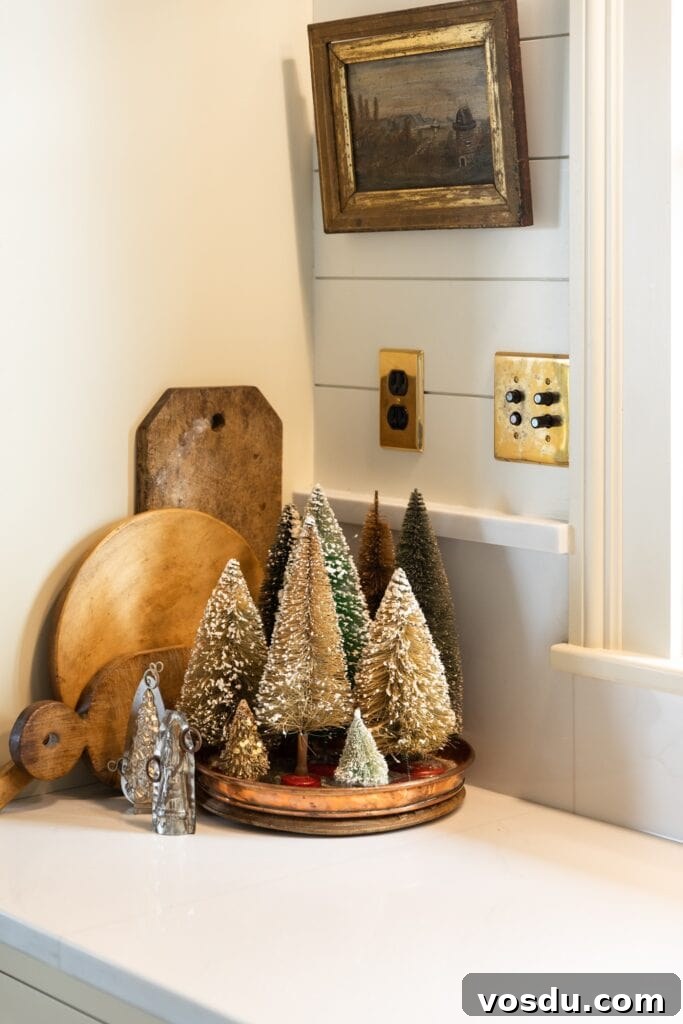 This Year’s Holiday Home Decor: Fresh Ideas to Transform Your Space 21 Brown colored bottle brush trees sitting on white countertop with wooden cutting boards behind and small picture hung above