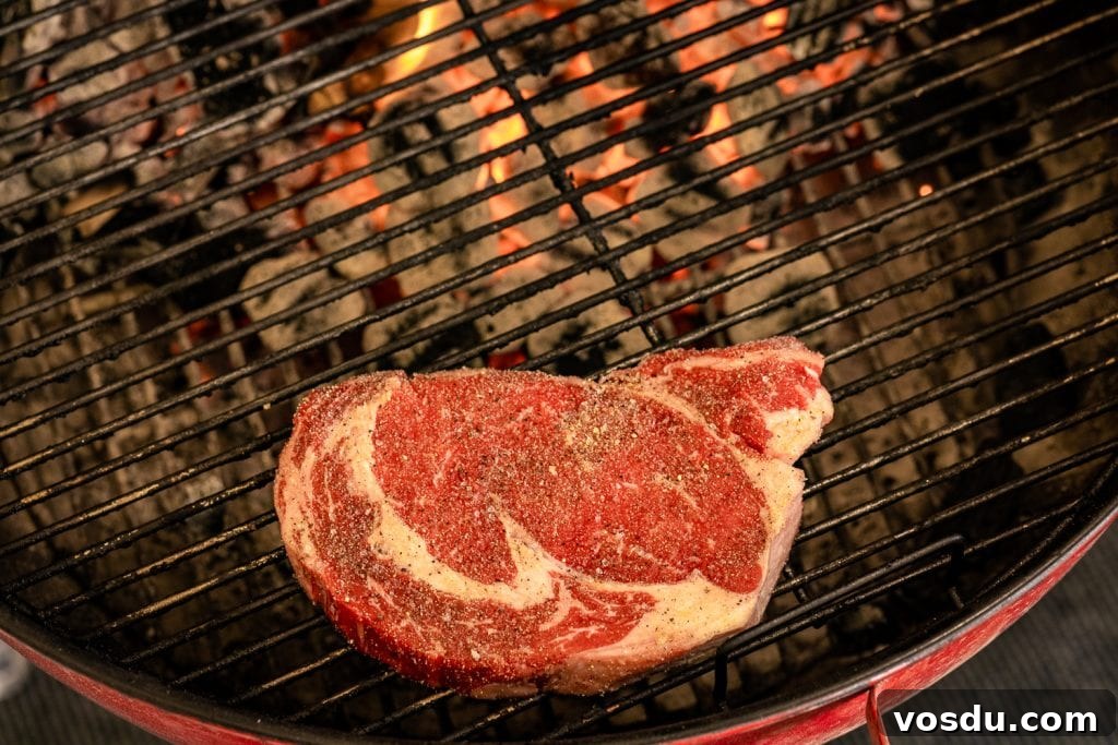 Ribeye steak over indirect heat side of a charcoal grill.