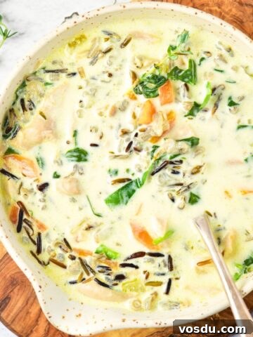 A bowl of chicken and wild rice soup on wooden board.