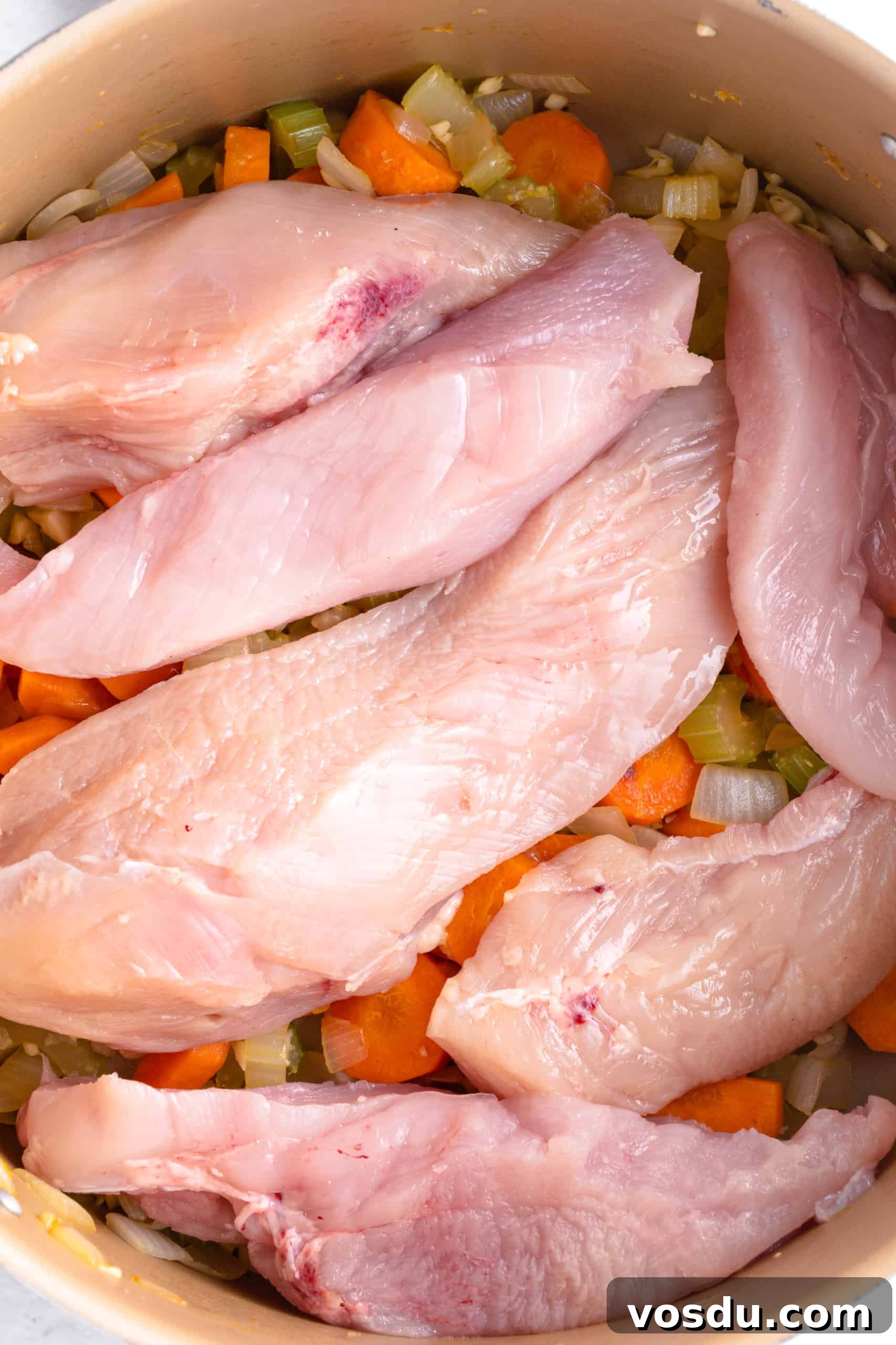 Gluten-Free Chicken Noodle Soup (Dairy-Free) Slices of chicken breasts on top of sautéed veggies in a pot.