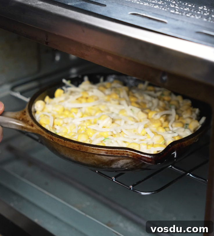 Korean Corn Cheese Recipe: Creamy Cheesy Corn Bake Tutorial 6 A cast iron dish filled with Korean corn cheese mixture being placed into the oven to bake until golden and bubbly.