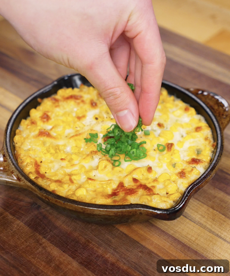 Korean Corn Cheese Recipe: Creamy Cheesy Corn Bake Tutorial 7 A hand sprinkling sliced scallion greens over the hot, bubbly Korean corn cheese for a fresh pop of color and flavor.