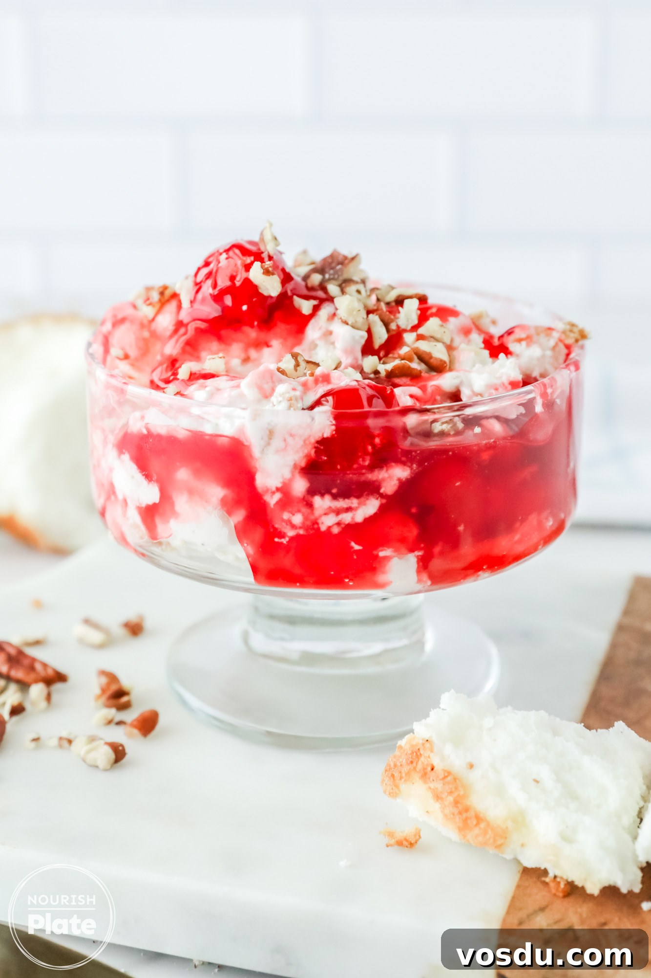 Cherries in the Snow served in a serving glass with a spoon on the side, with a crunchy pecan topping