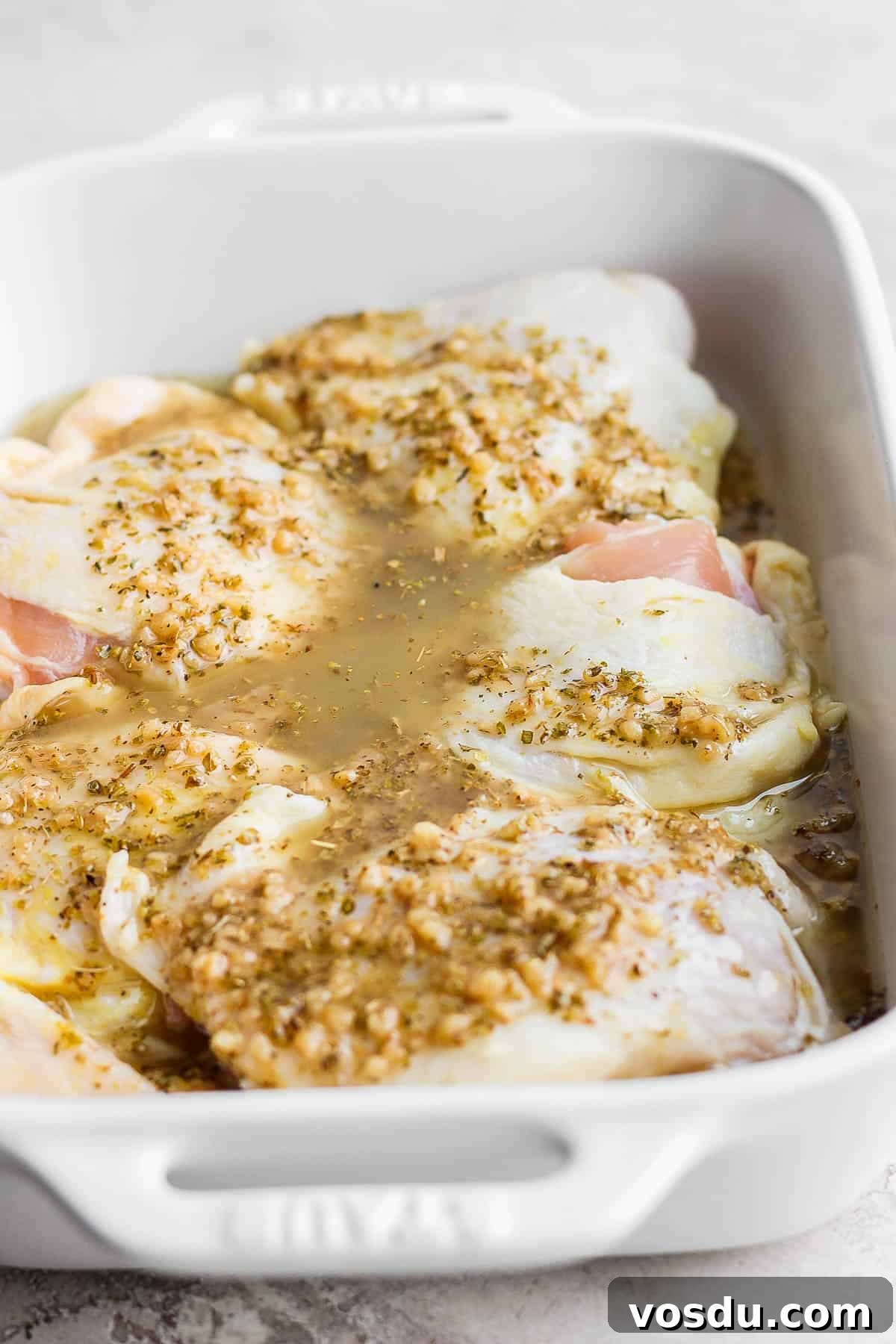 Greek-Style Chicken Marinade for Juicy, Flavorful Grilled Chicken 7 Greek marinade poured over the chicken thighs in the casserole dish.