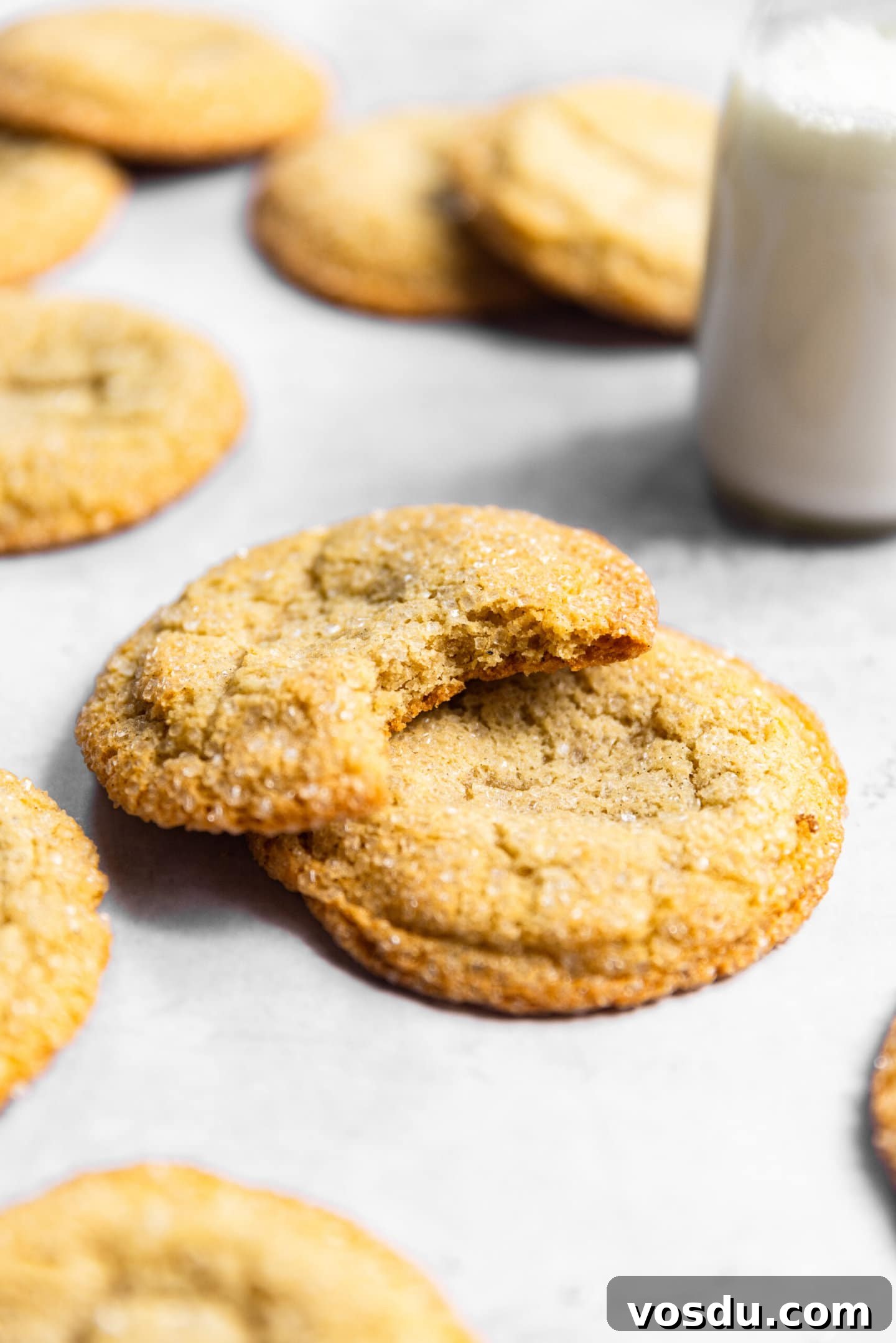 Simple Drop-Style Vanilla Sugar Cookies for Homemade Treats 2 Sugar cookies stacked on top of each other with a bite missing from one next to a glass of milk.