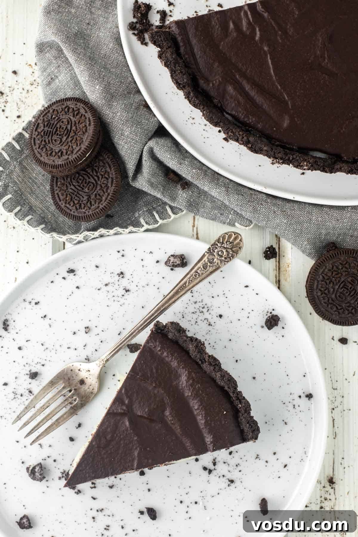 Decadent Oreo Cookie Tart Recipe 12 Slice of Oreo tart on plate with fork with dish towel and more Oreos.