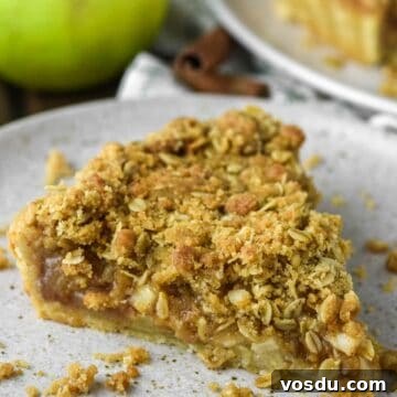 Slice of apple crumble tart on speckled plate.