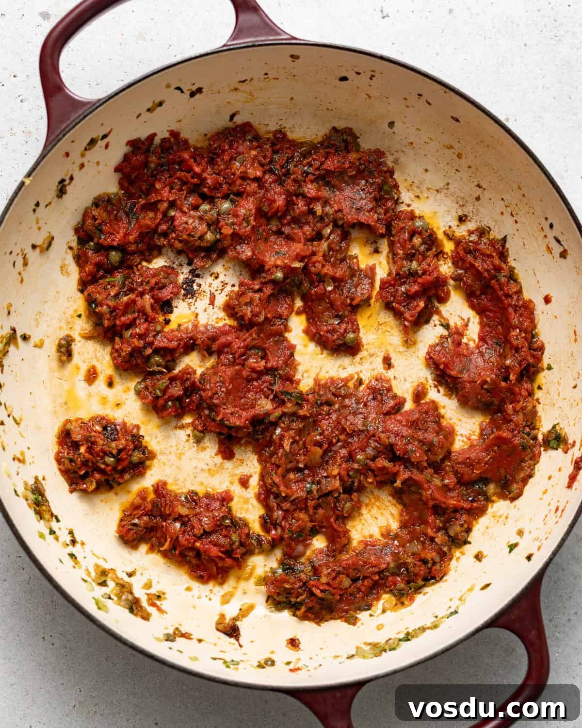 Shrimp Puttanesca Pasta Recipe with Tangy Tomato-Olive Sauce 7 cooked garlic, anchovies, tomato paste, and white wine in skillet.