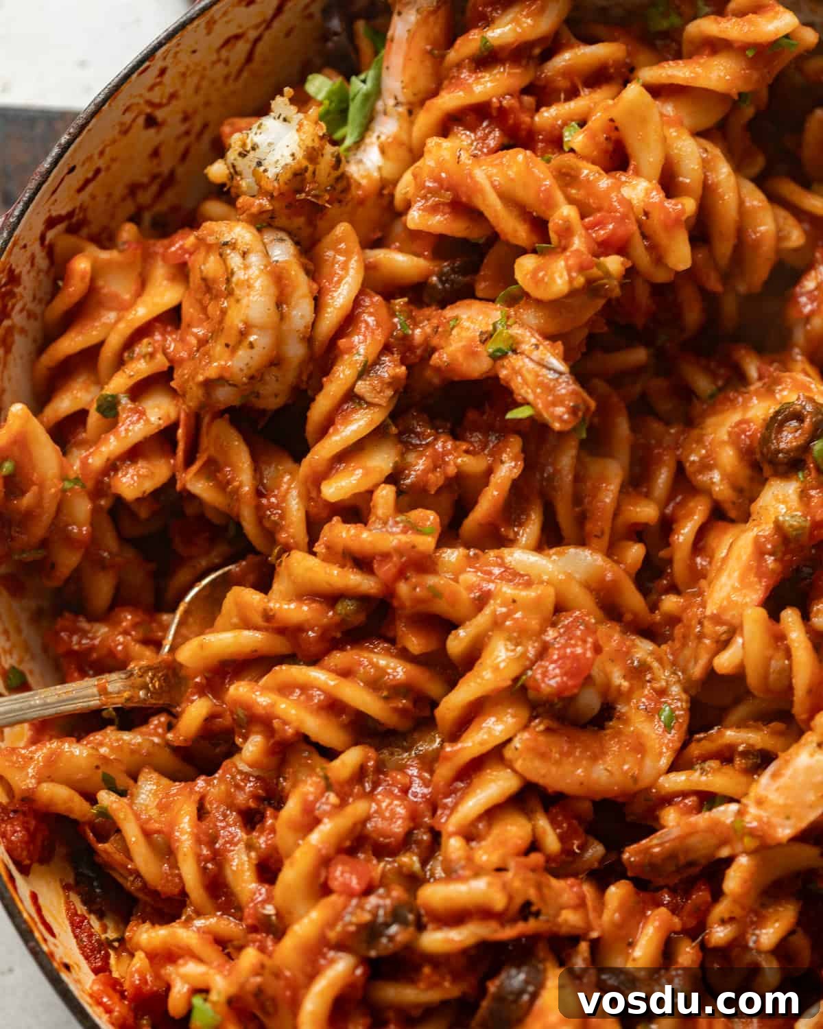 Shrimp Puttanesca Pasta Recipe with Tangy Tomato-Olive Sauce 8 up close photo of cooked pasta puttanesca tossed in sauce.