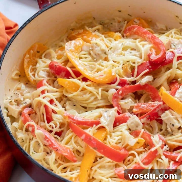 15 Quick Rotisserie Chicken Dinners for Busy Weeknights 4 Pasta with chicken, sliced onion, and strips of red and yellow bell peppers cooked in a white sauce in a skillet.