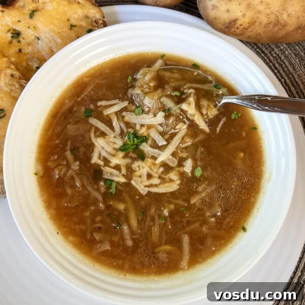 potato onion soup in bowl topped with shredded Parmesan