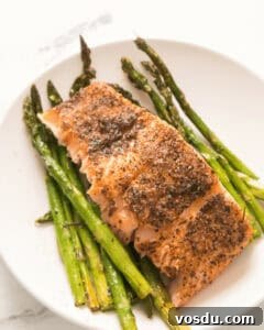 Chilled Asparagus and Tomato Salad with Lemon Vinaigrette 8 A white plate with asparagus and a seasoned salmon piece.
