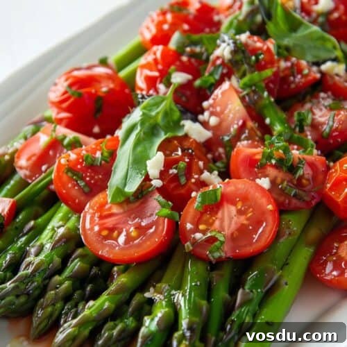 Chilled Asparagus and Tomato Salad with Lemon Vinaigrette 10 A plate of Cold Asparagus Salad topped with halved cherry tomatoes, fresh basil leaves, chopped chives, and crumbled cheese.