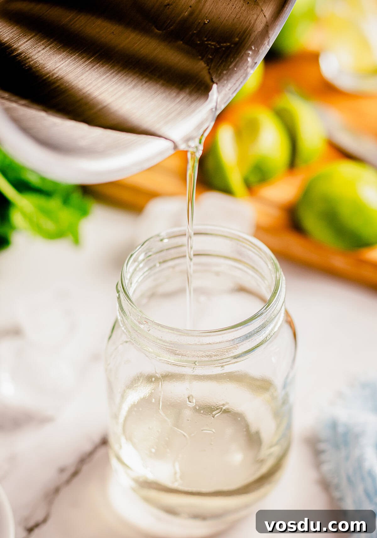 Simple syrup being poured from a saucepan into a mason jar