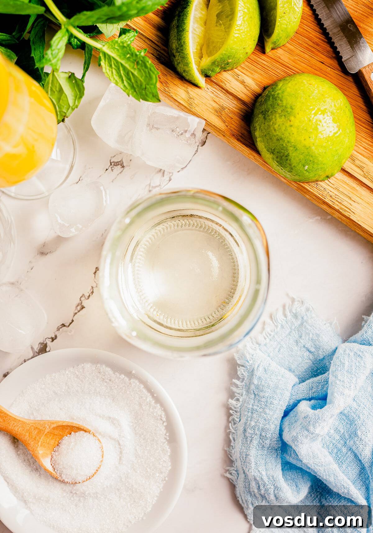 Simple syrup in a glass jar on a grey marble tabletop with ice