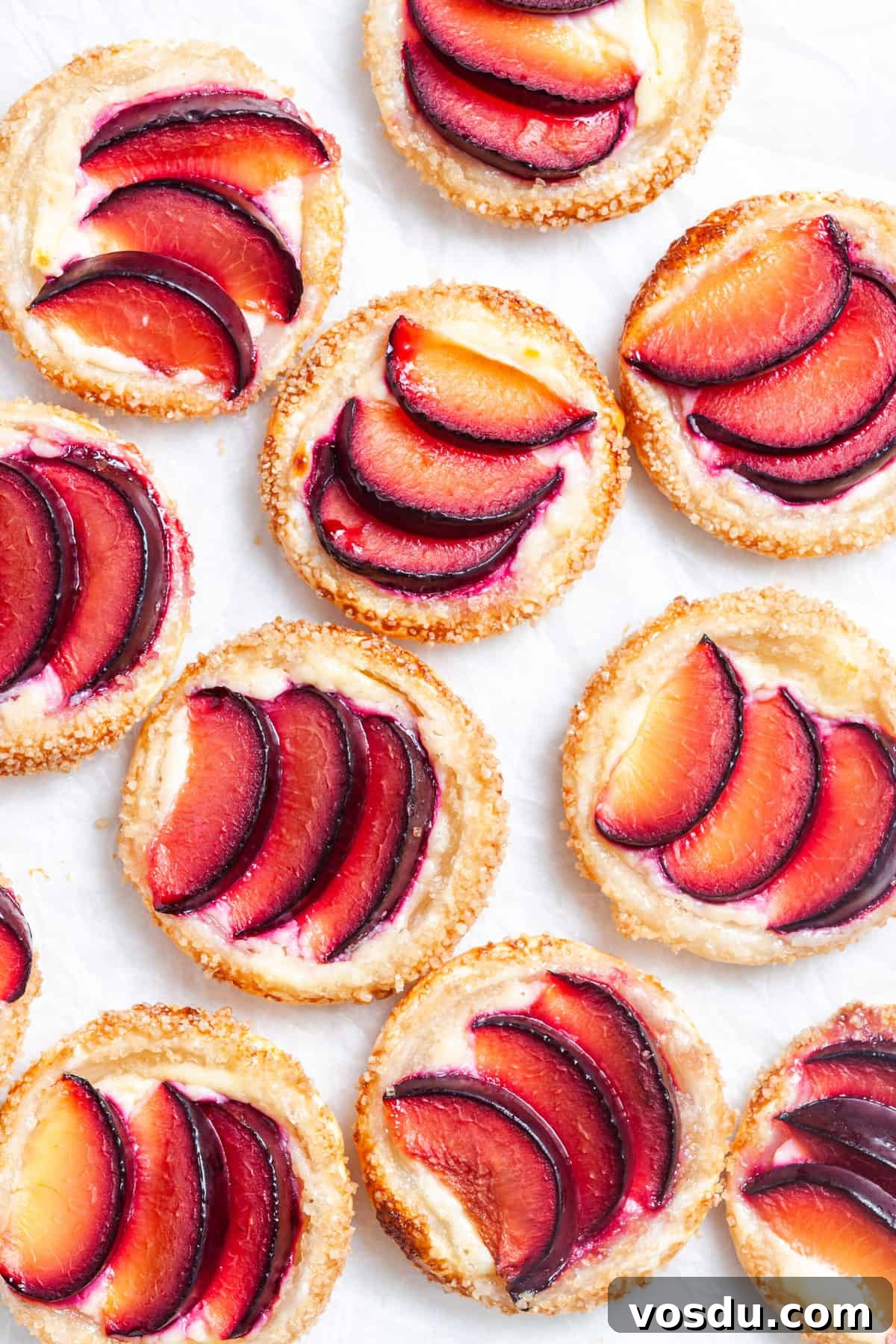 Mini Plum Tarts Recipe: Bite-Sized Homemade Fruit Pastries 2 up close shot of tarts on baking paper.